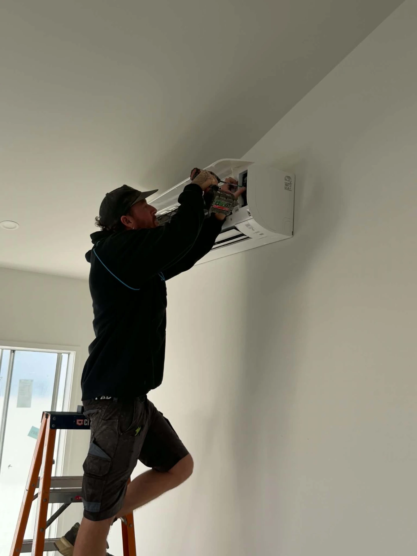 Millmac technician completing a split system installation inside a home