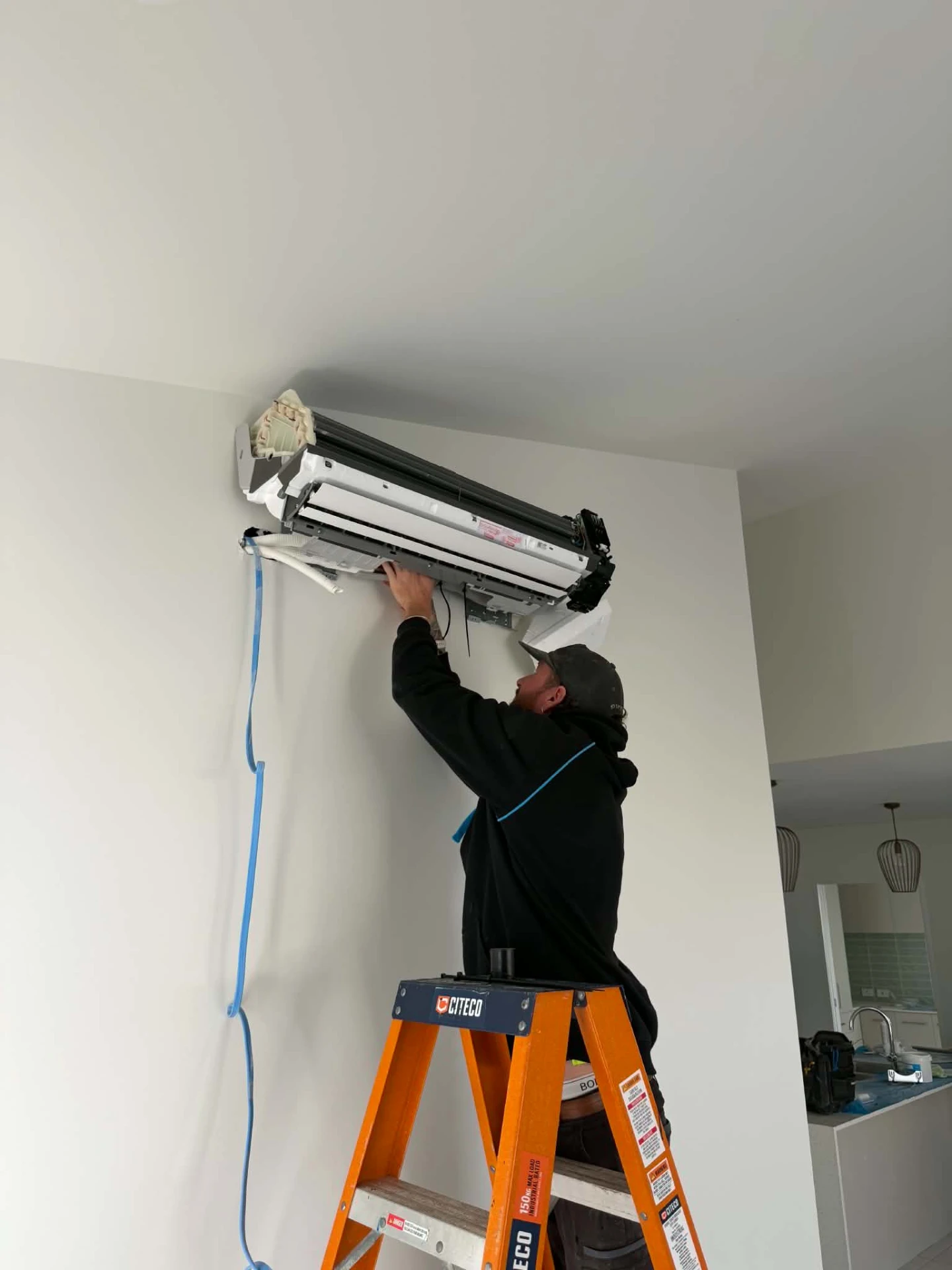 Millmac technician installing a wall-mounted split system air conditioner